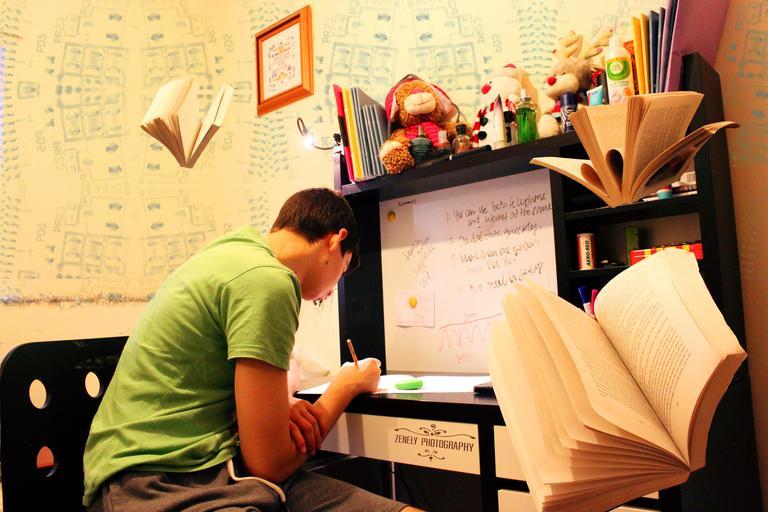 pokoj pro studenty – sedí u stolu a učí se